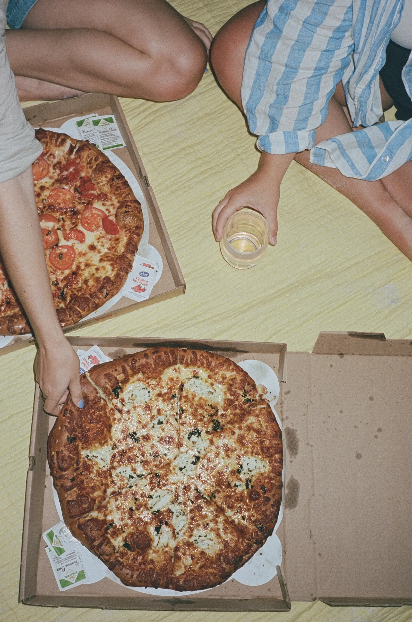 Friends sharing pizzas on a picnic blanket