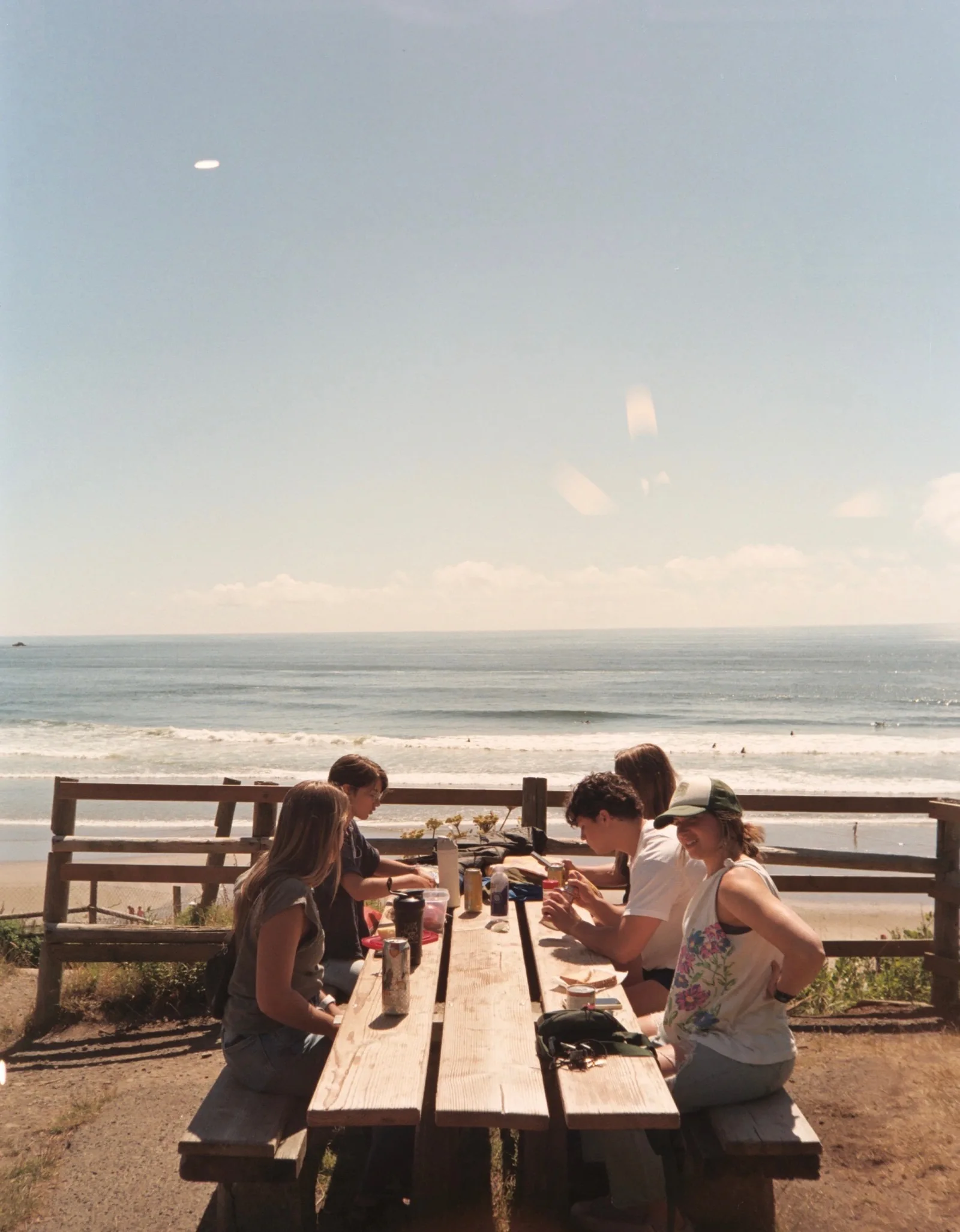 Friends eating at a long table beside the ocean