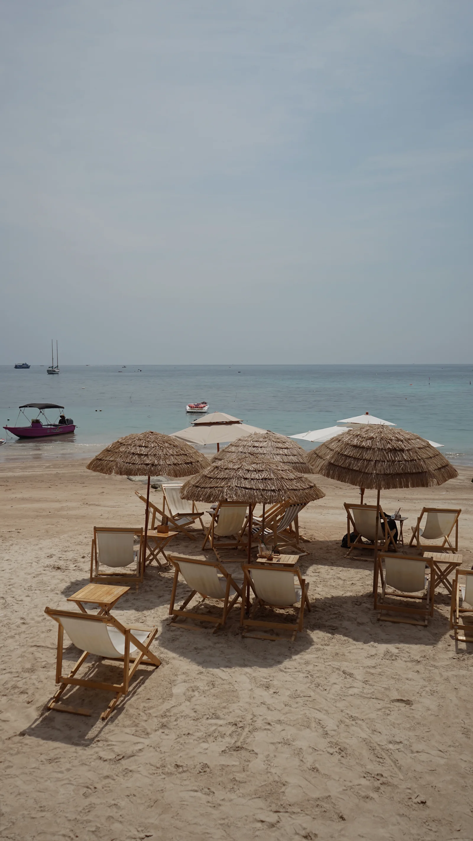 Straw parasols and boats along a quiet shore