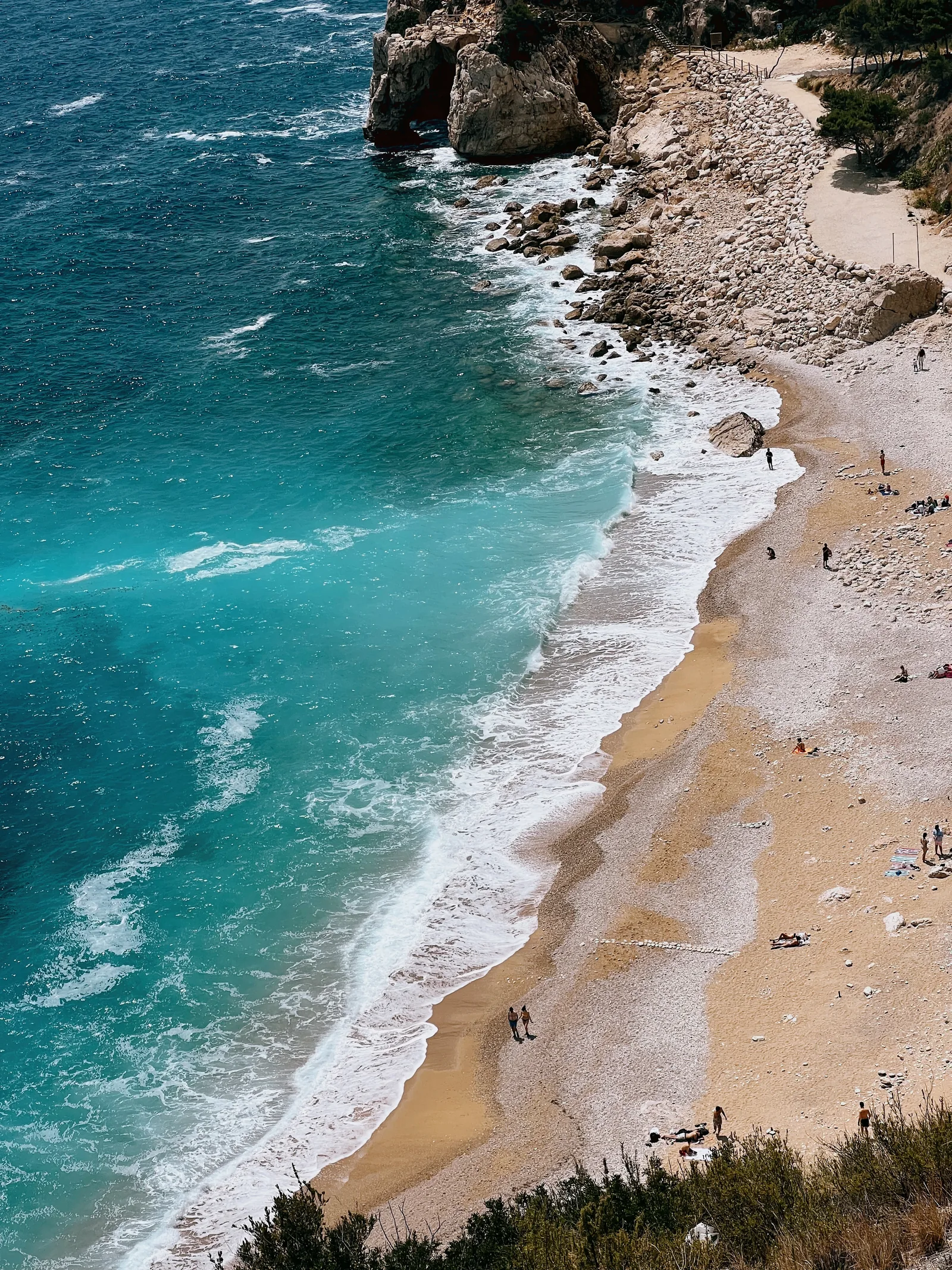Turquoise water meeting a small beach beneath cliffs